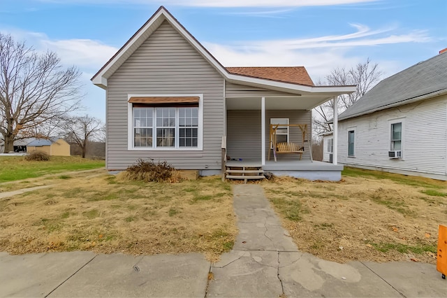 bungalow-style home featuring covered porch, a front lawn, and cooling unit