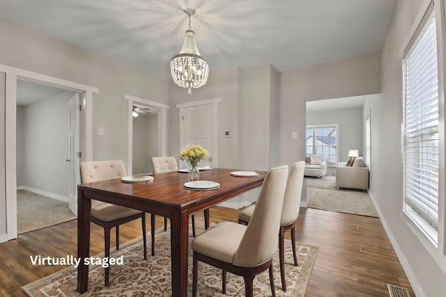 dining room with ceiling fan with notable chandelier and dark hardwood / wood-style floors