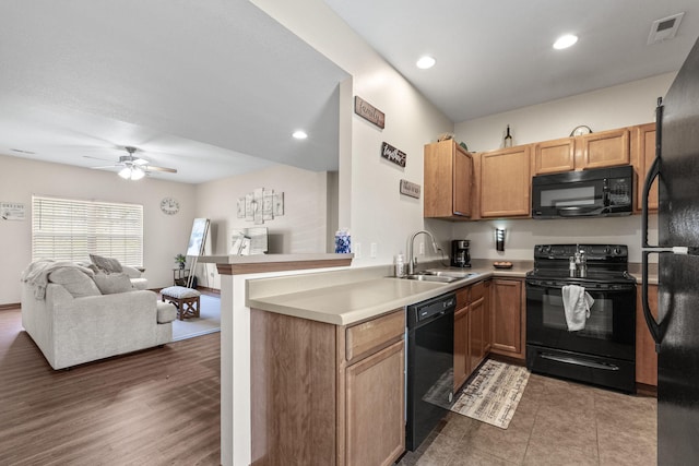 kitchen with kitchen peninsula, ceiling fan, dark wood-type flooring, sink, and black appliances