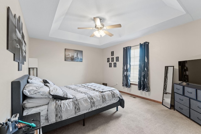 carpeted bedroom featuring a raised ceiling and ceiling fan