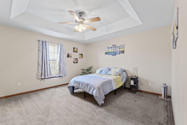 carpeted bedroom with ceiling fan and a tray ceiling