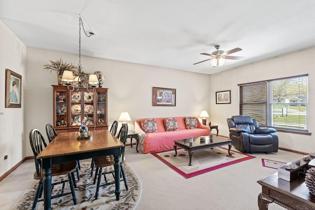 living room featuring carpet flooring and ceiling fan with notable chandelier