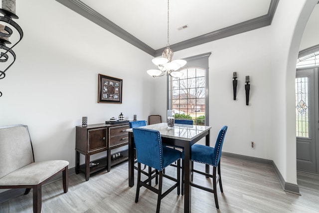 dining area with light wood-type flooring, crown molding, and a notable chandelier