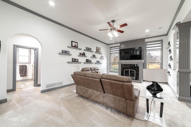 living room featuring ceiling fan, a fireplace, light colored carpet, and ornamental molding