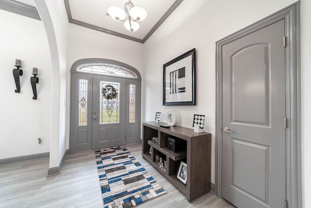 foyer featuring an inviting chandelier, ornamental molding, and light hardwood / wood-style flooring