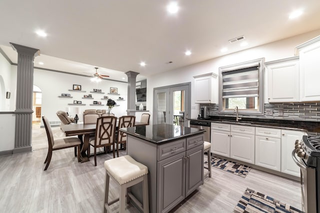 kitchen featuring ornate columns, white cabinetry, a center island, a breakfast bar, and appliances with stainless steel finishes