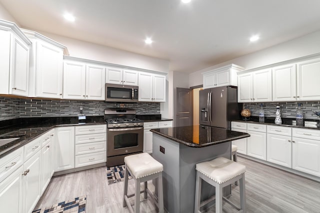 kitchen featuring light wood-type flooring, white cabinetry, stainless steel appliances, and a breakfast bar area