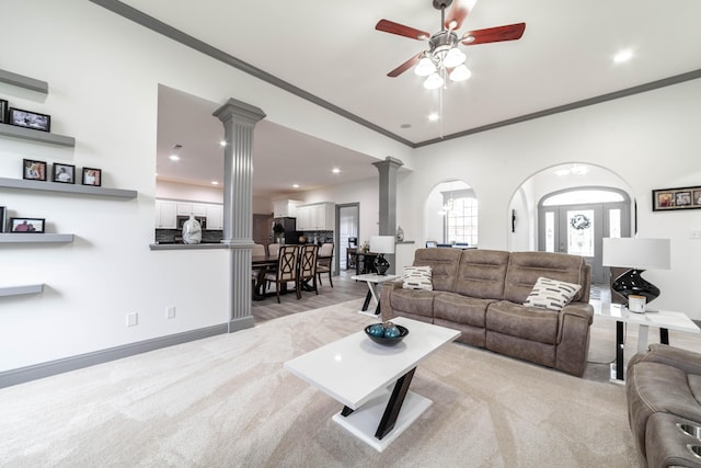 carpeted living room with ceiling fan, ornamental molding, and decorative columns