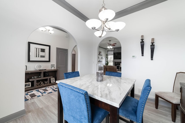 dining room featuring light hardwood / wood-style flooring, ceiling fan with notable chandelier, and ornamental molding