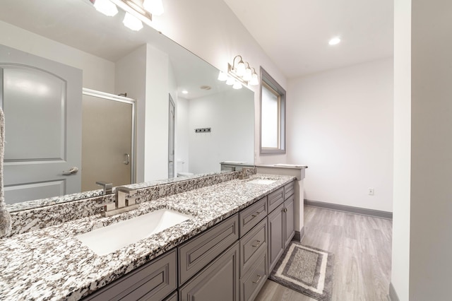 bathroom featuring hardwood / wood-style floors, vanity, and a shower with door