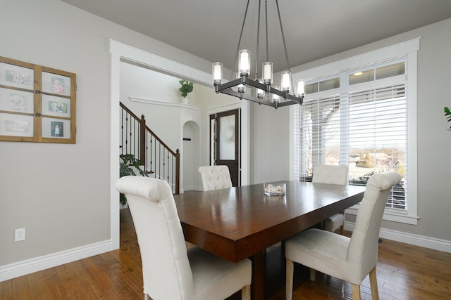 dining room featuring arched walkways, wood finished floors, baseboards, and an inviting chandelier