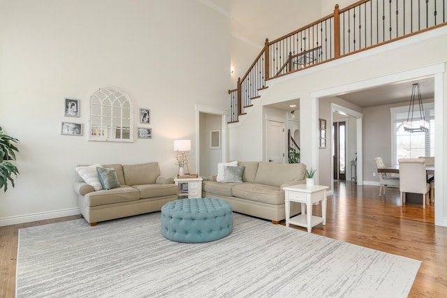 living room with a notable chandelier, stairway, baseboards, and wood finished floors