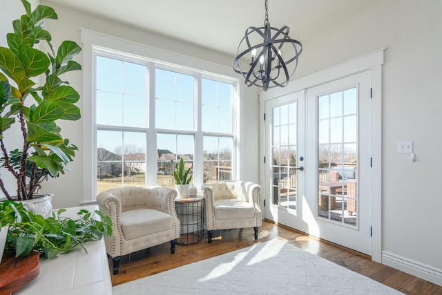 sunroom / solarium featuring french doors and an inviting chandelier