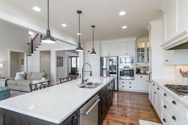 kitchen featuring stainless steel appliances, white cabinets, a sink, and wood finished floors