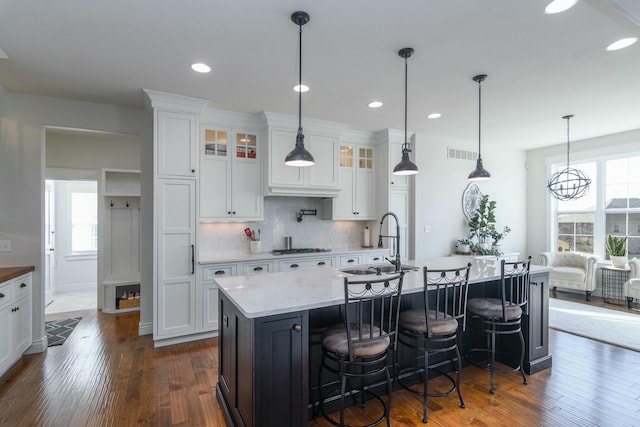 kitchen featuring tasteful backsplash, visible vents, a sink, and white cabinetry