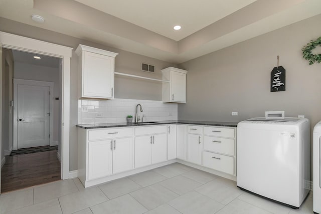 kitchen featuring a sink, visible vents, independent washer and dryer, open shelves, and dark countertops