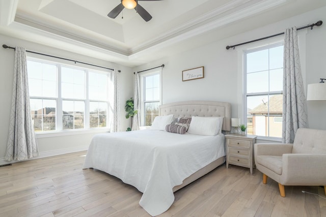 bedroom featuring light wood-style floors, a tray ceiling, and crown molding