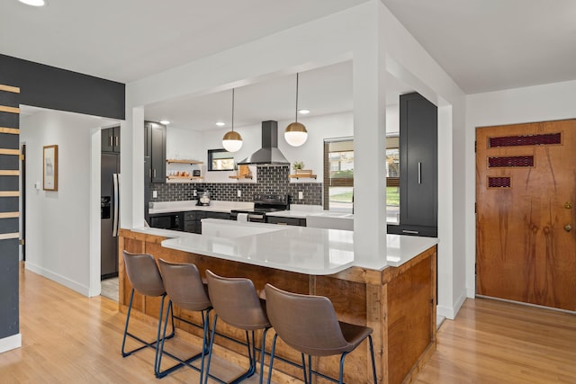 kitchen featuring range with electric stovetop, hanging light fixtures, a breakfast bar, and island range hood