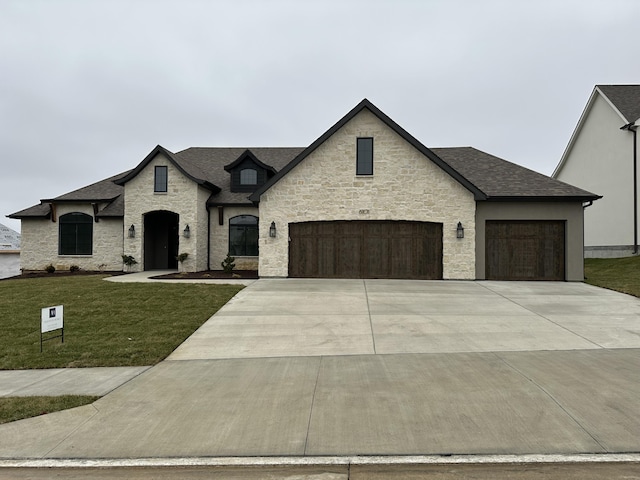 french provincial home with a front lawn and a garage