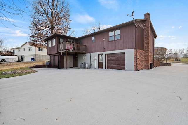 view of front of property featuring central AC unit, a garage, and a balcony