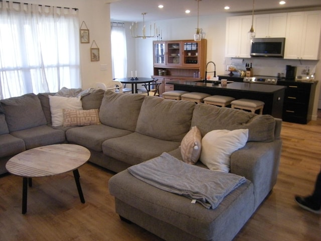 living room with hardwood / wood-style floors, a notable chandelier, and sink