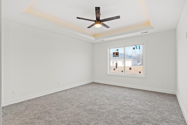 carpeted empty room with a tray ceiling and ceiling fan