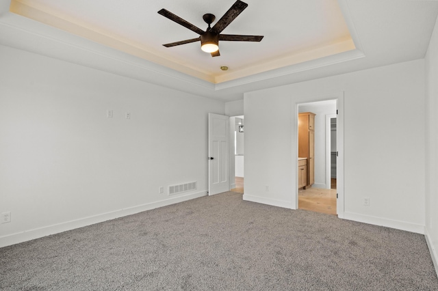 unfurnished bedroom featuring light colored carpet, connected bathroom, and a raised ceiling