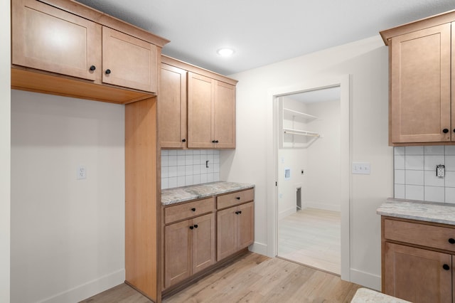 kitchen with tasteful backsplash, light hardwood / wood-style flooring, and light stone countertops