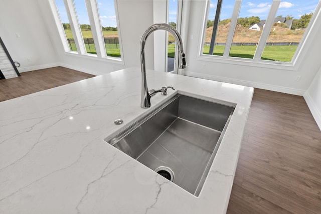 room details featuring dark hardwood / wood-style floors, light stone counters, and sink