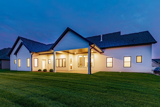 back house at dusk featuring a yard