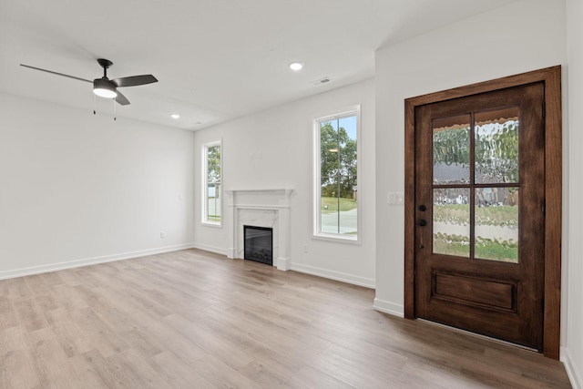 unfurnished living room with plenty of natural light, light wood-type flooring, and a fireplace