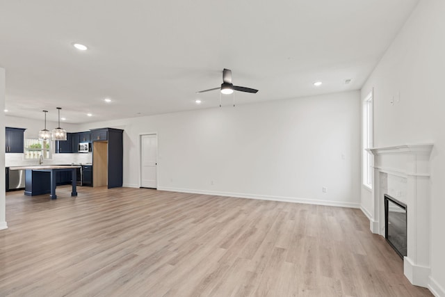 living room featuring hardwood / wood-style flooring, ceiling fan, sink, and a fireplace