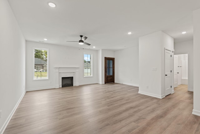 unfurnished living room featuring ceiling fan, light hardwood / wood-style floors, and a fireplace