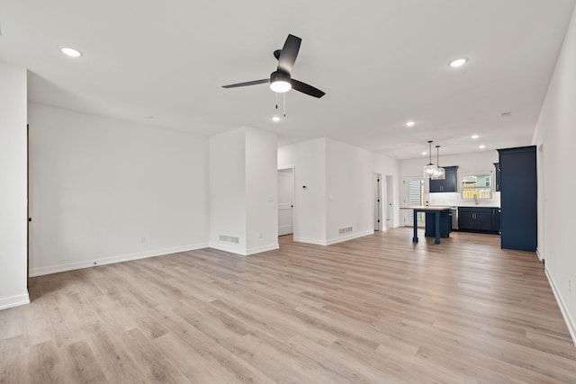 unfurnished living room with ceiling fan, light wood-type flooring, and sink