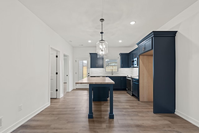 kitchen featuring hardwood / wood-style floors, backsplash, hanging light fixtures, sink, and appliances with stainless steel finishes