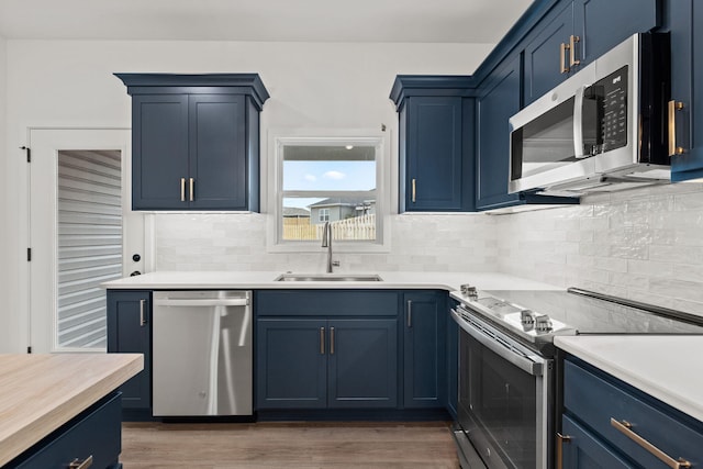 kitchen with blue cabinetry, backsplash, sink, and stainless steel appliances