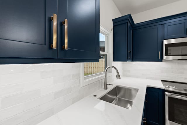 kitchen featuring backsplash, sink, stove, and blue cabinets