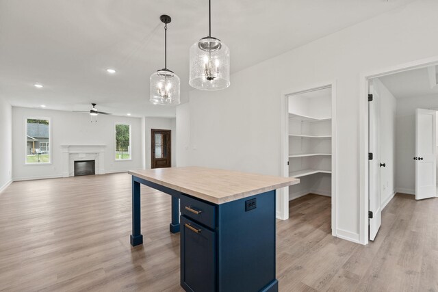 kitchen featuring blue cabinets, ceiling fan, decorative light fixtures, a premium fireplace, and a kitchen island