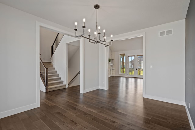 unfurnished dining area featuring dark hardwood / wood-style flooring, a chandelier, and french doors