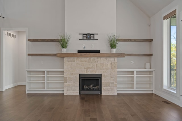 unfurnished living room featuring dark hardwood / wood-style flooring, a stone fireplace, and vaulted ceiling