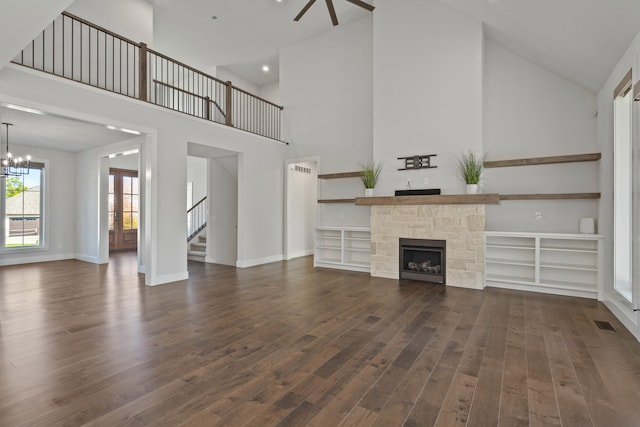 unfurnished living room featuring a chandelier, a fireplace, high vaulted ceiling, and dark wood-type flooring