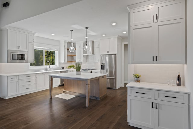 kitchen featuring pendant lighting, stainless steel appliances, white cabinetry, and tasteful backsplash