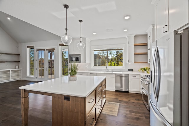 kitchen featuring white cabinetry, pendant lighting, vaulted ceiling, a kitchen island, and appliances with stainless steel finishes