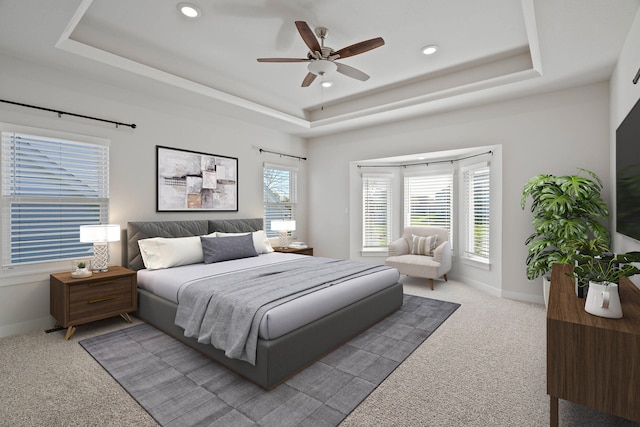 carpeted bedroom featuring a raised ceiling and ceiling fan