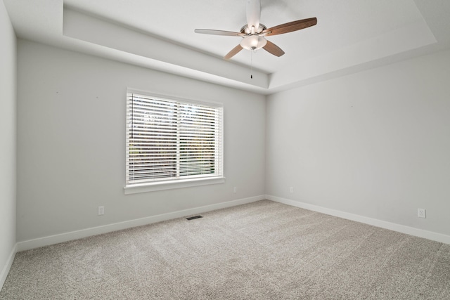 carpeted empty room with a tray ceiling and ceiling fan