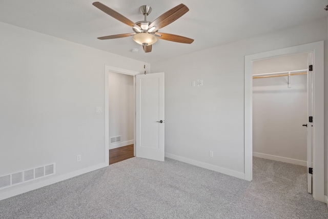 unfurnished bedroom featuring carpet flooring, a walk in closet, a closet, and ceiling fan