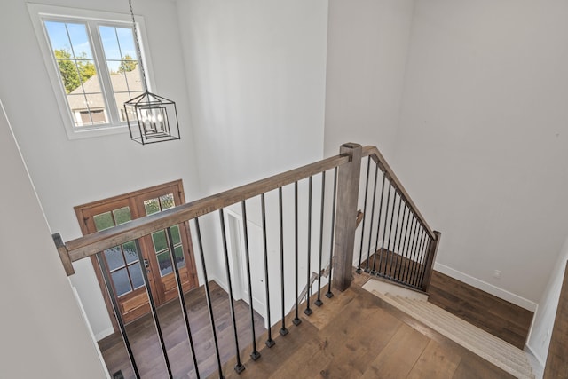 staircase with hardwood / wood-style flooring, french doors, and a chandelier