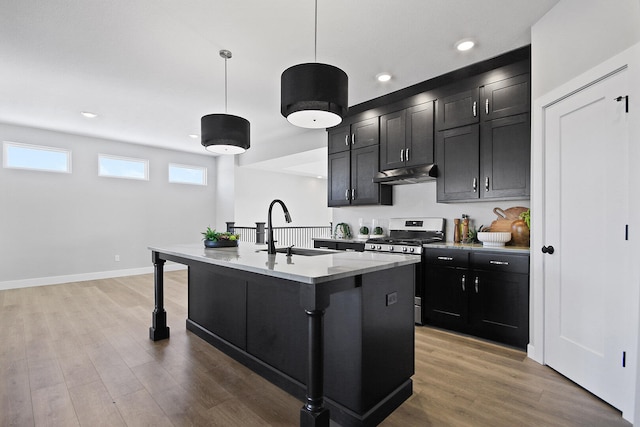 kitchen featuring hardwood / wood-style floors, a kitchen island with sink, sink, hanging light fixtures, and gas range