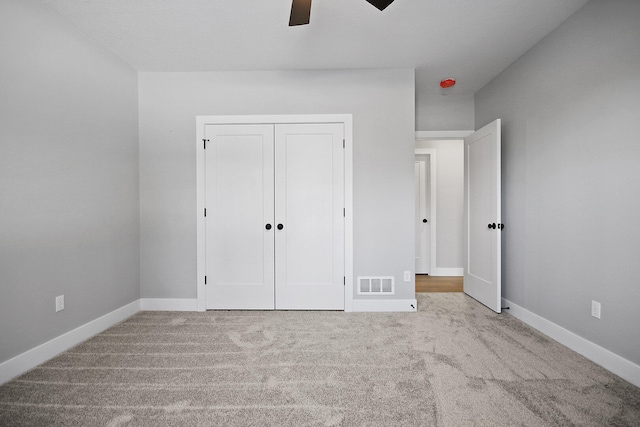 unfurnished bedroom featuring ceiling fan, a closet, and light carpet