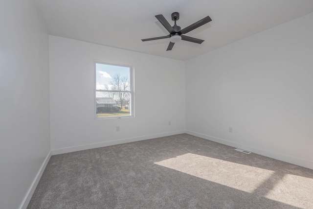 carpeted spare room with baseboards, visible vents, and ceiling fan